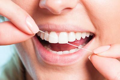 A patient flossing her teeth in Monroe, WA