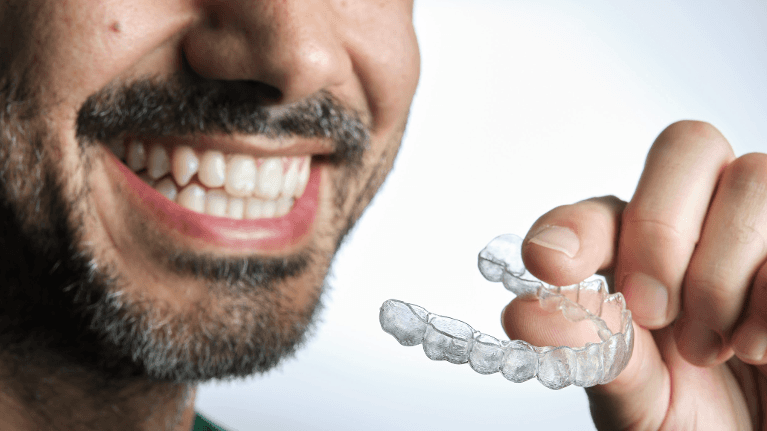 A man holding Invisalign clear aligners at Skyvalley Dental in Monroe, WA.