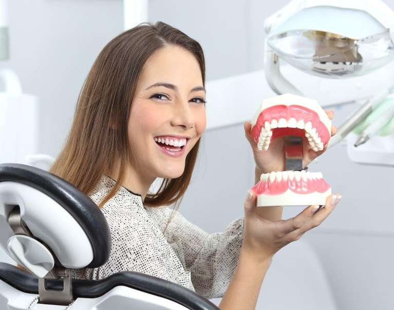 A female patient holding a tooth model in Monroe, WA