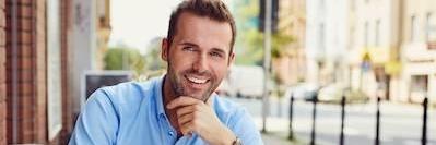 man smiling while sitting in outdoor cafe