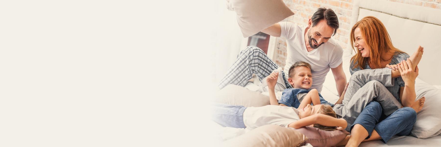 Father, mother, son, and daughter having a pillow fight on bed